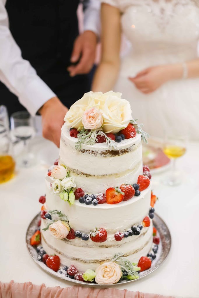 Three-tier wedding cake adorned with fresh berries and flowers, perfect for celebrations.