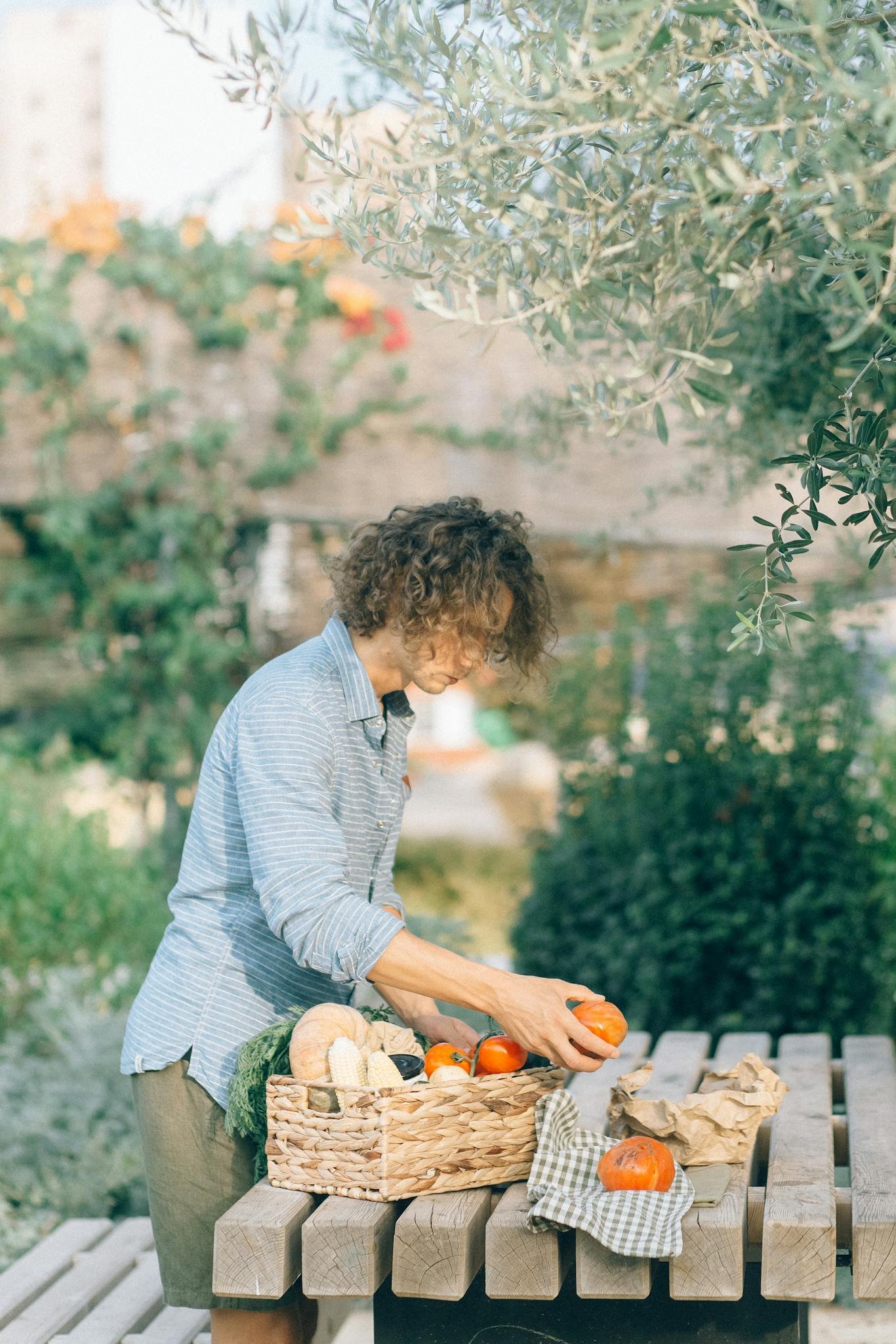 A man picking fresh vegetables from a garden basket, showcasing organic harvest.