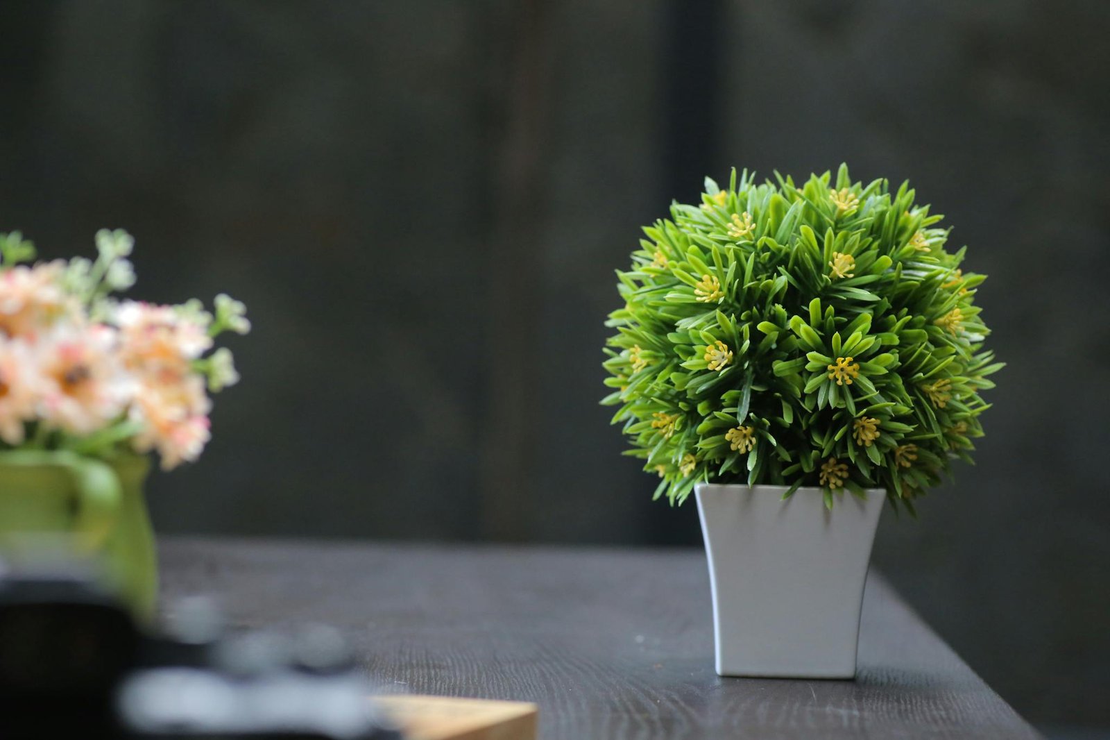 Aesthetic indoor plant arrangement featuring artificial greenery in a modern pot on a wooden table.